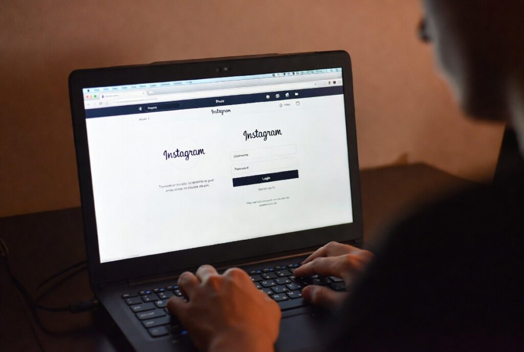 A person viewing a smartphone screen showing an Instagram direct message log and a separate private monitoring dashboard on a laptop how to hack someones instagram